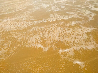Soft wave of white ocean on the sandy beach. Background.