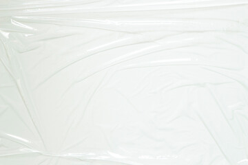 Transparent plastic wrap on white color background. Crumpled wrinkled plastic cellophane. Reflecting light and shadow on creases and folds in plastic surface. Texture overlay effect template