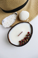 Fototapeta na wymiar original decorative candle in a coconut. natural soy wax candle. straw hat and straw bag