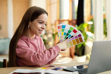 Remote designer courses. Happy teen girl having online lesson via laptop, holding color samples and...