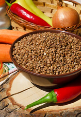 Buckwheat in a bowl, red pepper, carrots and onions on the board.
