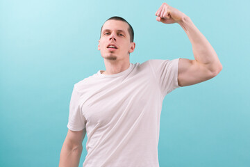 A man in a white t-shirt shows his biceps on a blue background. Confident. Emotional. Energy....