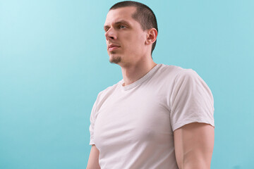 A half-side view of a man in a white t-shirt on a blue background. Modern. One. Studio. White. Young. Casual. Fashion. Lifestyle. Authority. Concentration. Hold. Isolated