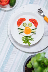Sunny side egg breakfast, decorated for kids, with animal character. Served with vegetables.