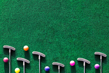 Multiple mini golf clubs and balls on putting green background with copy space - obrazy, fototapety, plakaty