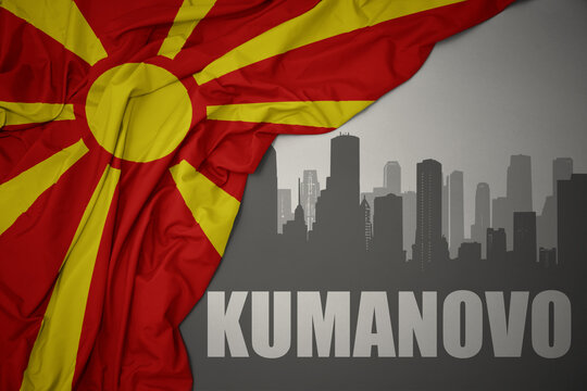 abstract silhouette of the city with text Kumanovo near waving national flag of macedonia on a gray background.