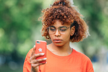 serious afro american girl looking at mobile phone