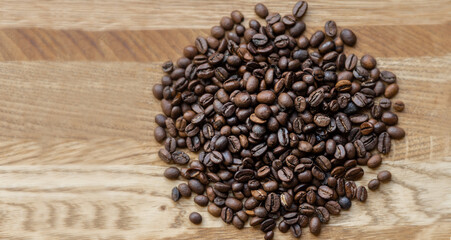 Large grains of roasted coffee lie on a wooden background