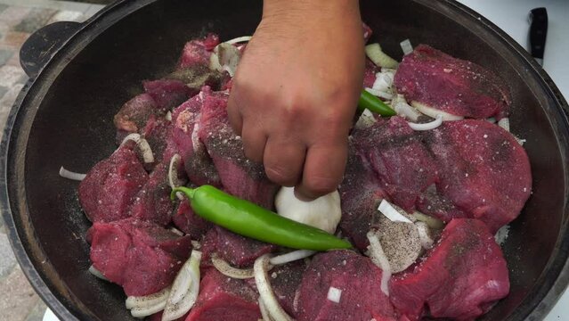 the cook puts beef meat and vegetables in a cauldron