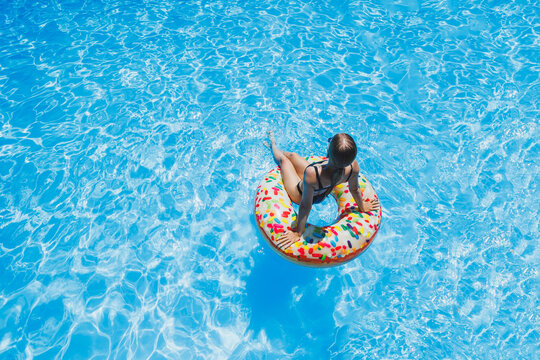 Beautiful woman in sunglasses in the pool floats on an inflatable swimming ring in a black swimsuit, summer photo, swimming photography, summer woman photos
