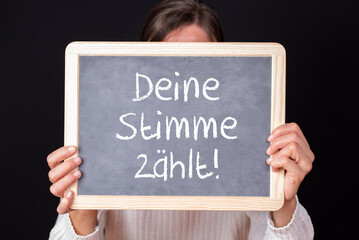 Frau mit einer Tafel auf der Deine Stimme zählt steht