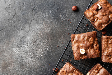 Chocolate brownie cake dessert with nuts on baking rack on dark background top view