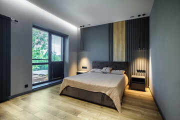 Modern and loft bedroom with dark and grey style. Dark headboard and wooden floor with glass window