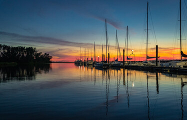 Large yacht harbor in orange sunset light, luxury summer cruise, sailboats in summer sunset.