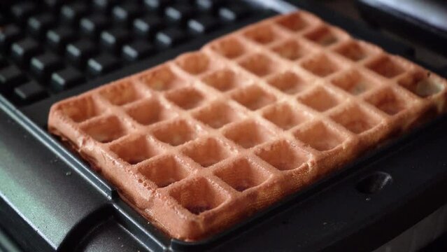 Fresh cooked breakfast. Gold fried Belgian waffles in iron waffle machine. Close up. Selective focus