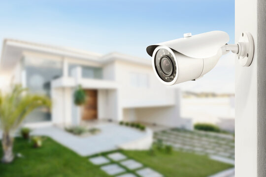 Three quarter view of varifocal surveillance camera, with a house on background