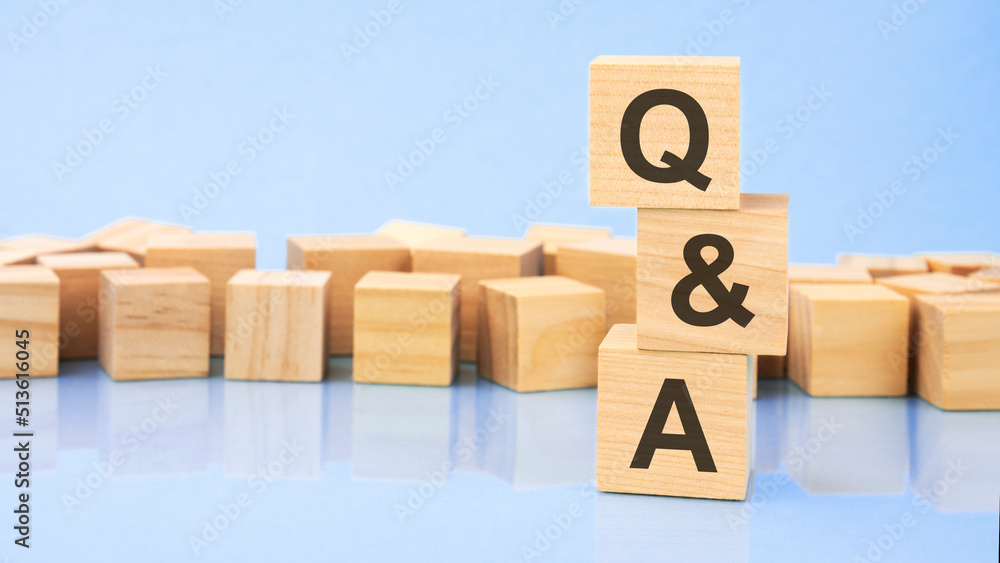 Aufkleber q and a. wooden cubes. blocks lie on a black background. stacks with coins. inscription on the cubes
