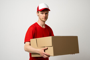 Courier man in a red uniform holding a cardboard box. Parcels Delivery Service Concept.