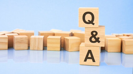 Q and A. wooden cubes. blocks lie on a black background. stacks with coins. inscription on the cubes is reflected from the surface of the table. selective focus. Q and A - Question and Answer