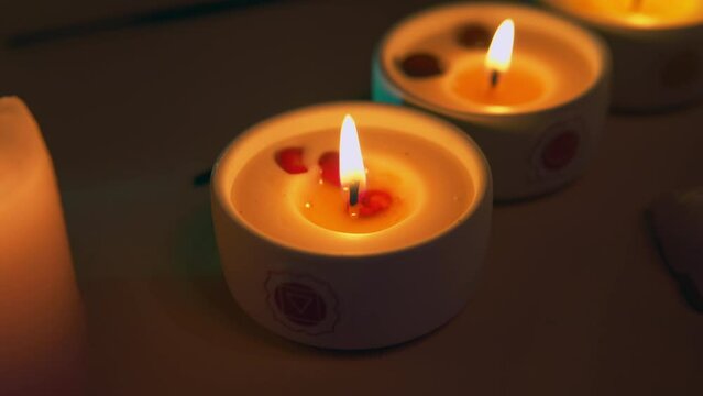 Chakra candle's flame close up. Candle burning. Dried flowers.