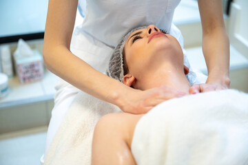 Fototapeta na wymiar Young woman receiving decollete massage in beauty salon