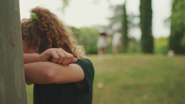 Three girls friends pre-teenage playing Hide-and-seek . Close-up of teenage girl counting with closed eyes while others run away
