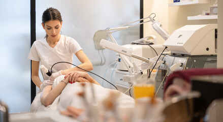 Female beautician giving anti-aging rejuvenation procedure to client at beauty salon