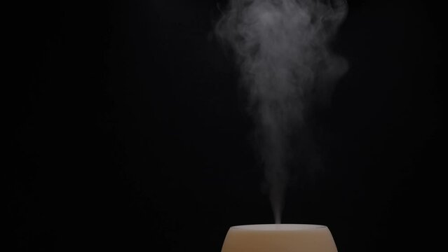 Diffuser for essential oils diffusing steam on black background. Nobody