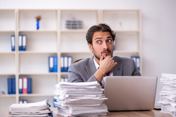 Fototapeta premium Young male employee and too much work in the office