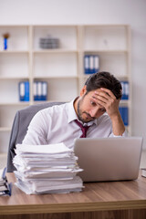 Young male employee and too much work in the office