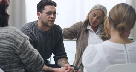 Young and diverse support group meeting with a professional mature female therapist. Group of employees looking serious during a team counselling session. Mental health in the workplace