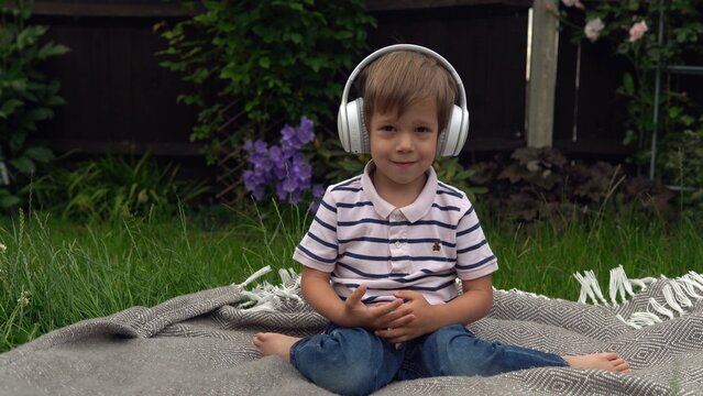handsome smiling boy listening to music on headphones. Children and technology. Love of music, children's dreams hobbies. Talented happy little child resting outside. Childhood, musicality, hobby