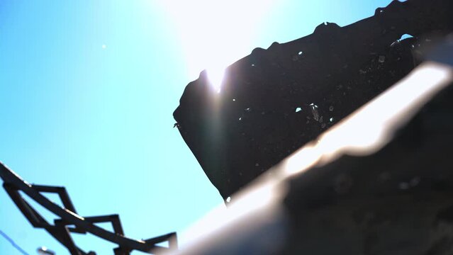 Sunrays shining outdoors at background of ruined roof tiles with bullet holes. Destroyed ruined house outdoors in sunshine in war zone in Ukraine