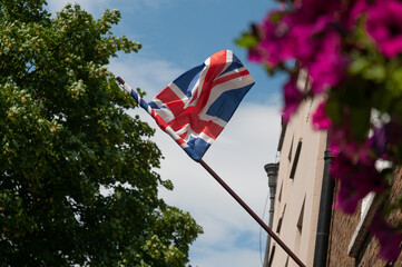 union jack hanging from pole with flowers in foreground 