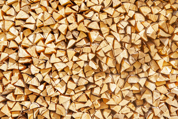 Textured firewood background of chopped wood for kindling and heating the house, a woodpile with stacked firewood. Concept of economic fuel crisis.