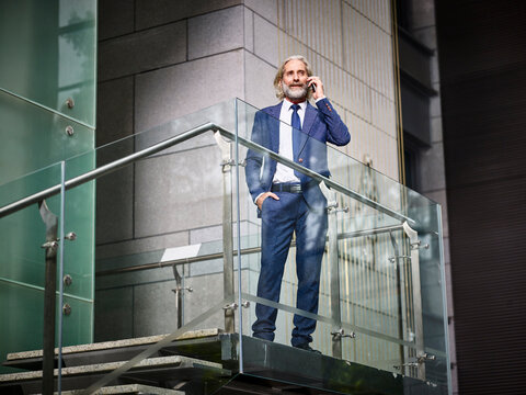 mature caucasian businessman making a call using mobile phone inside modern office building