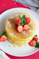 Tasty pancakes with strawberries, honey and coconut.