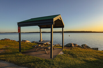 Picnic table with roof on the Clarence River at sunset. Iluka NSW Australia