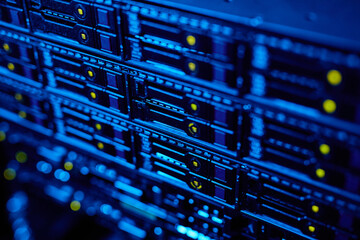 Closeup background image of blade servers with blinking neon light stacked in data center, copy...