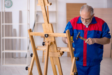 Old male carpenter repairing drawing easel