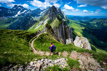 Hiker is walking along one of the most beautiful altitude paths of the Säntis massive