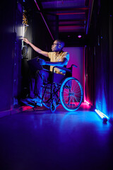Fototapeta na wymiar Full length portrait of person with disability working at system administrator in server room lit by neon light