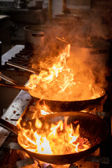 Manos que cocinan en un restaurant, con sarten sobre fuego. Salteado de carnes