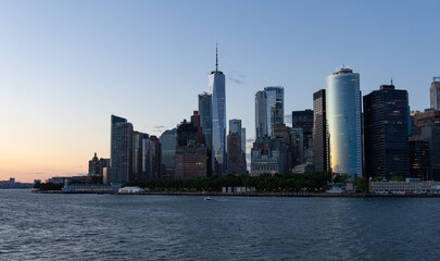 Lower Manhattan skyline at sunset viewed from the water.