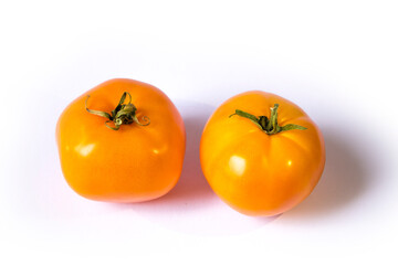 two yellow tomatoes lie on a white background