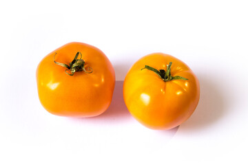 two yellow tomatoes lie on a white background