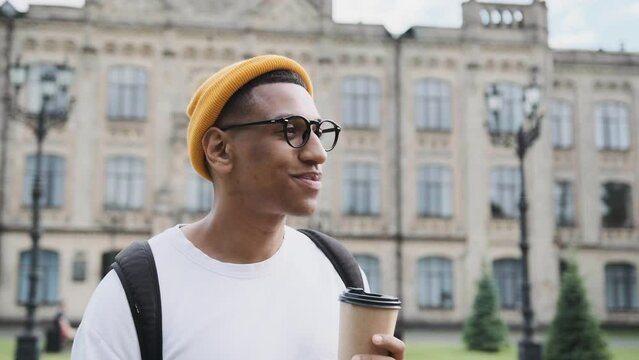Portrait of a stylish casual mulat smiling young man. African american student is drinking cofee and smiling.