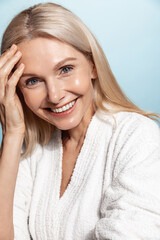 Vertical shot of middle aged woman in her 50s, has glowing natural face, nourished clear skin,...