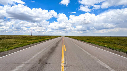 A road stretches to the horizon. Above are little fluffy clouds. It is impossibly flat. Route 73 in South Dakota.