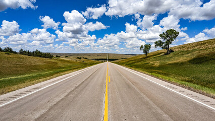 Fototapeta na wymiar A road stretches to the horizon. Above is a sea of little fluffy clouds. Route 73 in South Dakota.